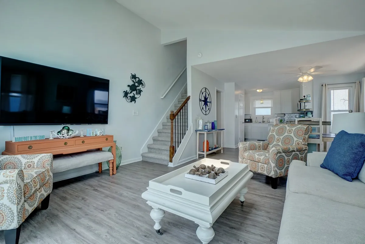 A spacious, inviting living room featuring a large flat-screen TV, comfortable decorative chairs, and a central coffee table. The layout encourages group gatherings, movie nights, or relaxed conversation, with decor that creates a cozy, welcoming atmosphere ideal for friends.