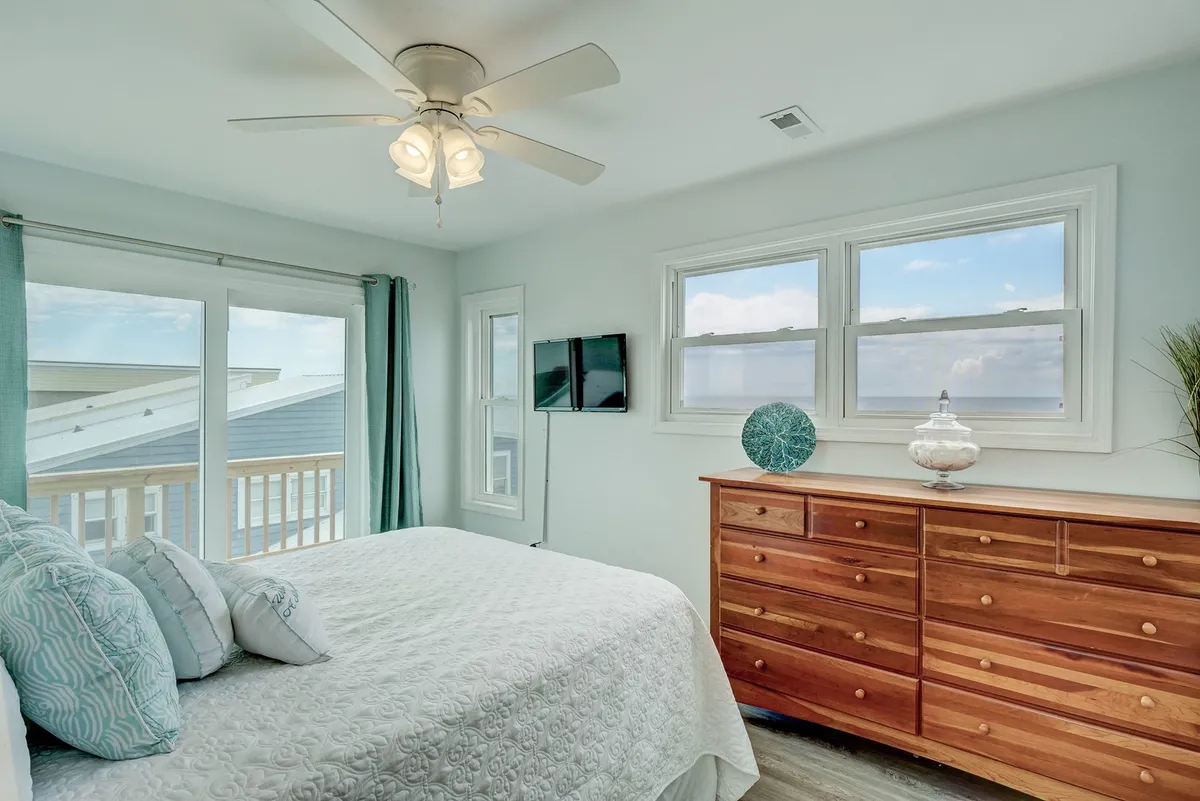A serene bedroom with a comfortable bed adorned with decorative pillows, a dresser, and windows that offer a view outside. The space is inviting and tranquil, encouraging restful nights after adventurous days.